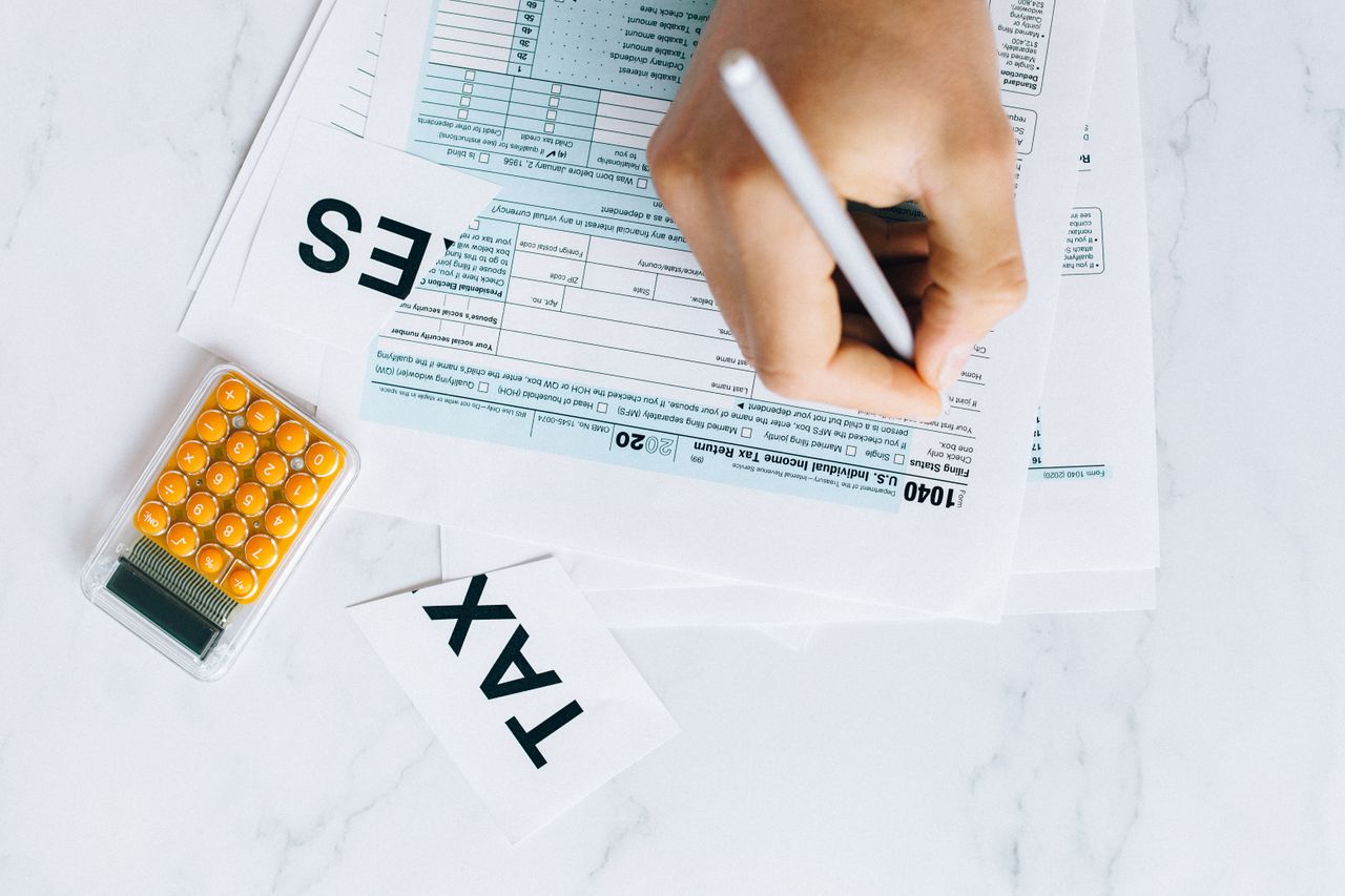 The Art of Drawing Readers In: Your attractive post title goes here Close-up of hand writing on tax form with calculator nearby on white surface.