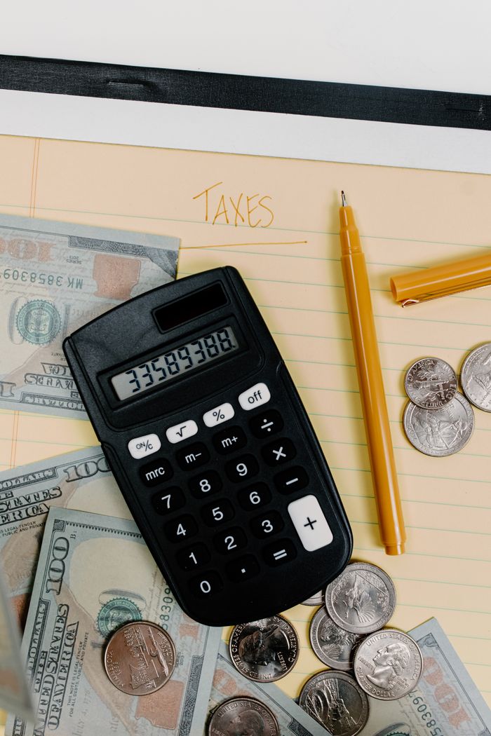 Mastering the First Impression: Your intriguing post title goes here A financial planning setup with calculator, cash, and coins on a notepad labeled 'Taxes.'